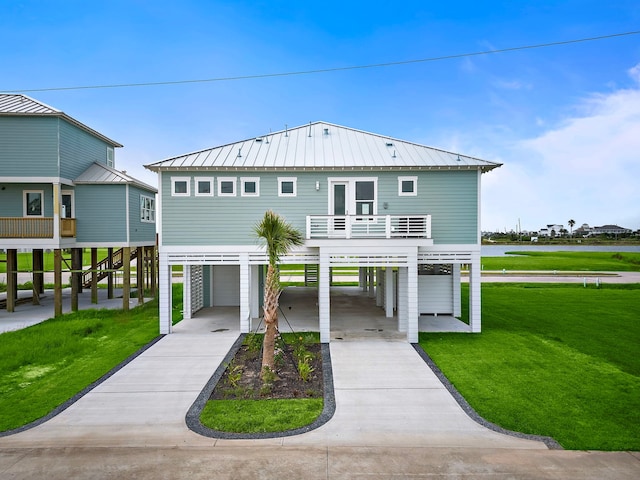 raised beach house with a garage, a balcony, a carport, and a front yard