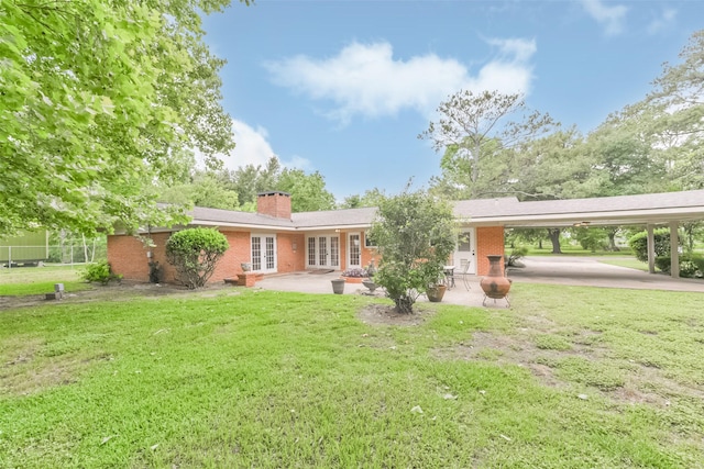 exterior space with a lawn, a carport, and french doors