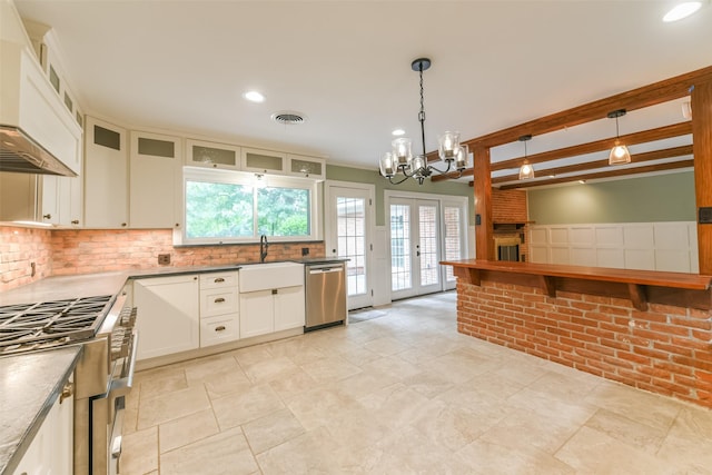 kitchen with pendant lighting, sink, white cabinets, custom exhaust hood, and stainless steel dishwasher