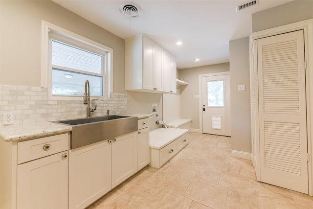 kitchen featuring tasteful backsplash, sink, light stone countertops, and white cabinets