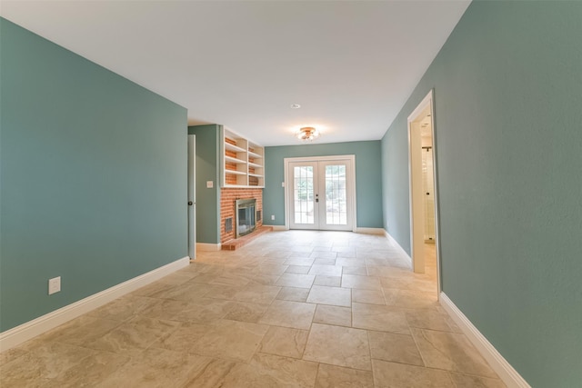 unfurnished living room with built in shelves, a fireplace, and french doors