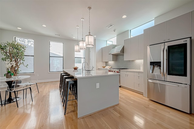 kitchen featuring decorative light fixtures, white cabinets, a kitchen breakfast bar, stainless steel appliances, and a center island with sink