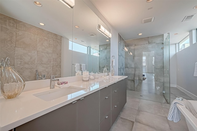 bathroom featuring tile walls, vanity, a shower with shower door, and a healthy amount of sunlight