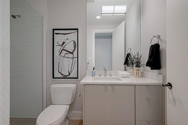 bathroom featuring vanity, a tile shower, and toilet