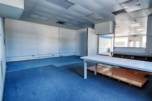 interior space with a paneled ceiling and dark colored carpet