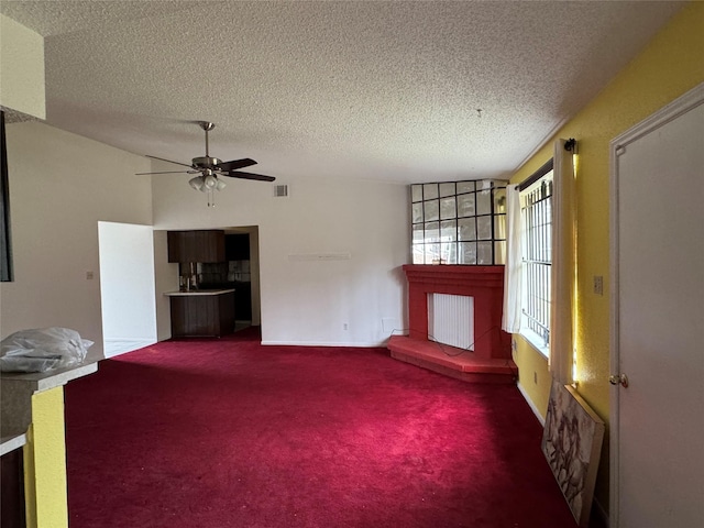 unfurnished living room with ceiling fan, carpet, and a textured ceiling