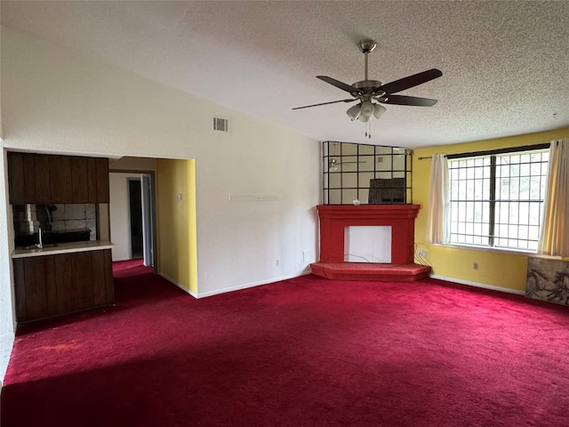 unfurnished living room featuring vaulted ceiling, ceiling fan, a textured ceiling, and dark carpet