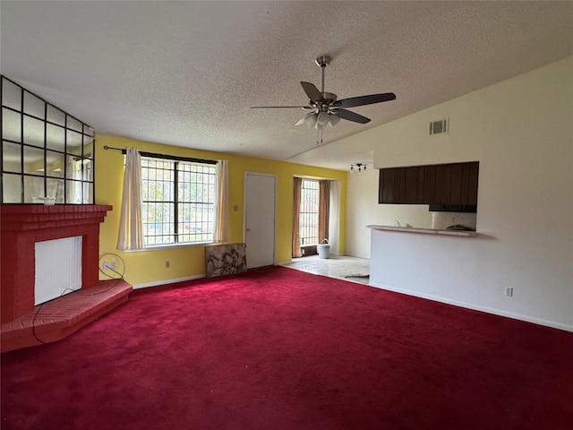 unfurnished living room with ceiling fan, vaulted ceiling, a textured ceiling, and carpet