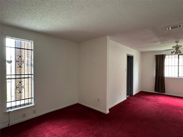 empty room featuring ceiling fan, a textured ceiling, and dark carpet