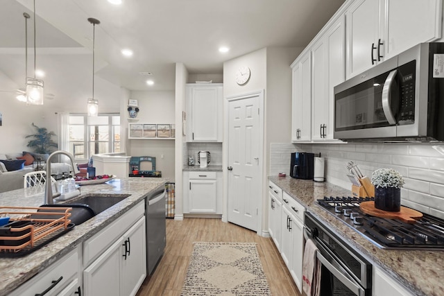 kitchen featuring decorative light fixtures, stainless steel appliances, light stone countertops, light hardwood / wood-style floors, and white cabinets