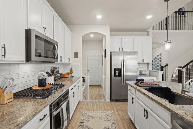 kitchen with stainless steel appliances, hanging light fixtures, sink, and white cabinets