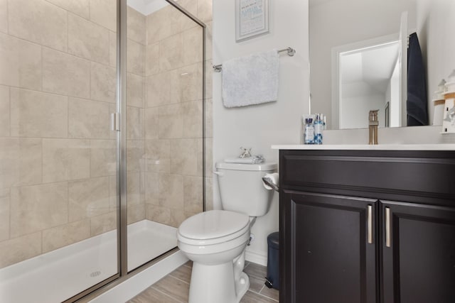 bathroom featuring hardwood / wood-style flooring, vanity, a shower with door, and toilet