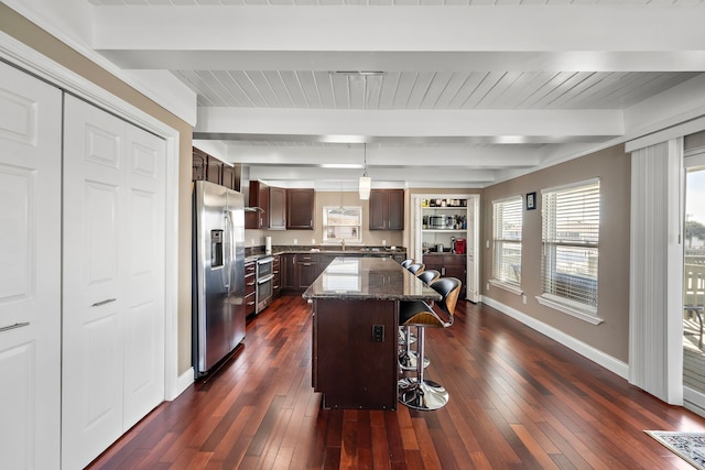 kitchen featuring a kitchen bar, a center island, stainless steel fridge with ice dispenser, dark stone countertops, and beamed ceiling