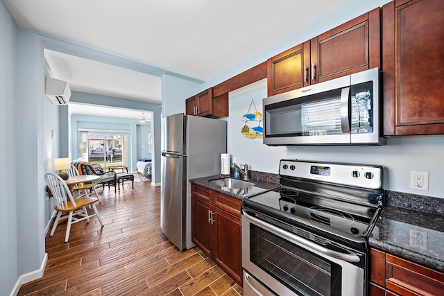 kitchen featuring sink, dark stone countertops, appliances with stainless steel finishes, a wall unit AC, and ceiling fan