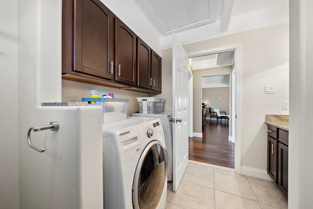 laundry room with independent washer and dryer, cabinets, and light tile patterned floors