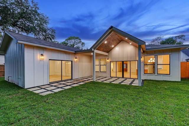 back house at dusk with a yard and a patio area