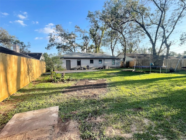 view of yard featuring a trampoline and a fenced backyard