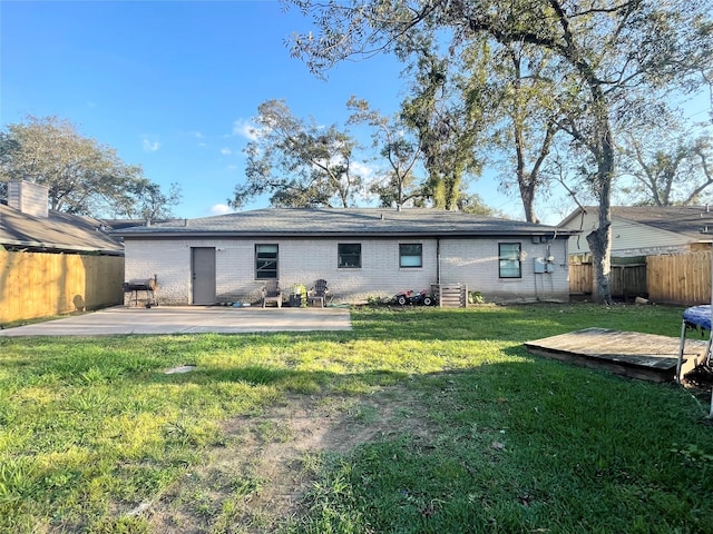 back of property with brick siding, a patio area, fence, and a yard