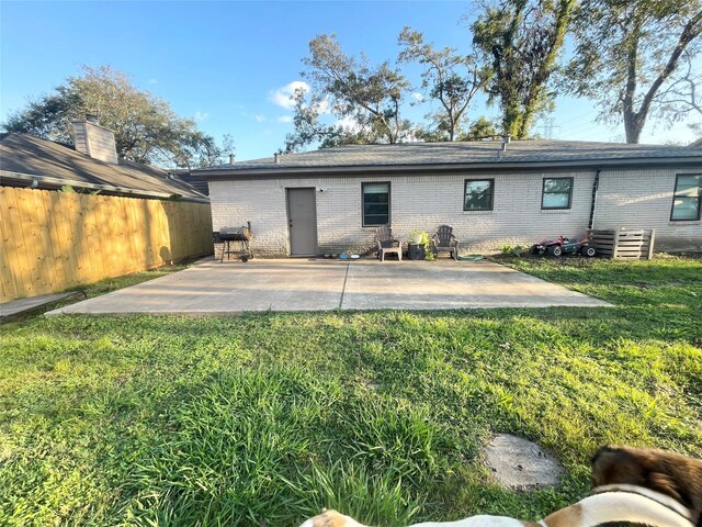 back of house with brick siding, a yard, fence, and a patio