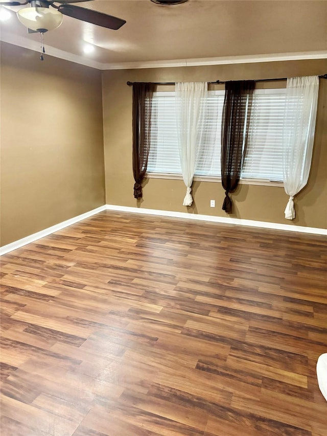 empty room featuring ceiling fan, baseboards, and wood finished floors