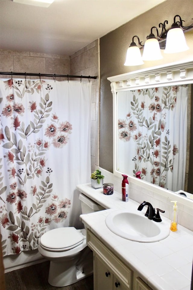 full bath with curtained shower, vanity, and toilet