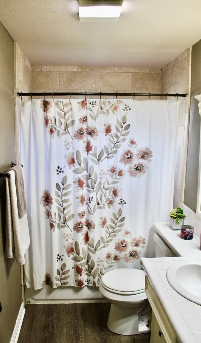 bathroom featuring shower / tub combo with curtain, vanity, toilet, and wood finished floors