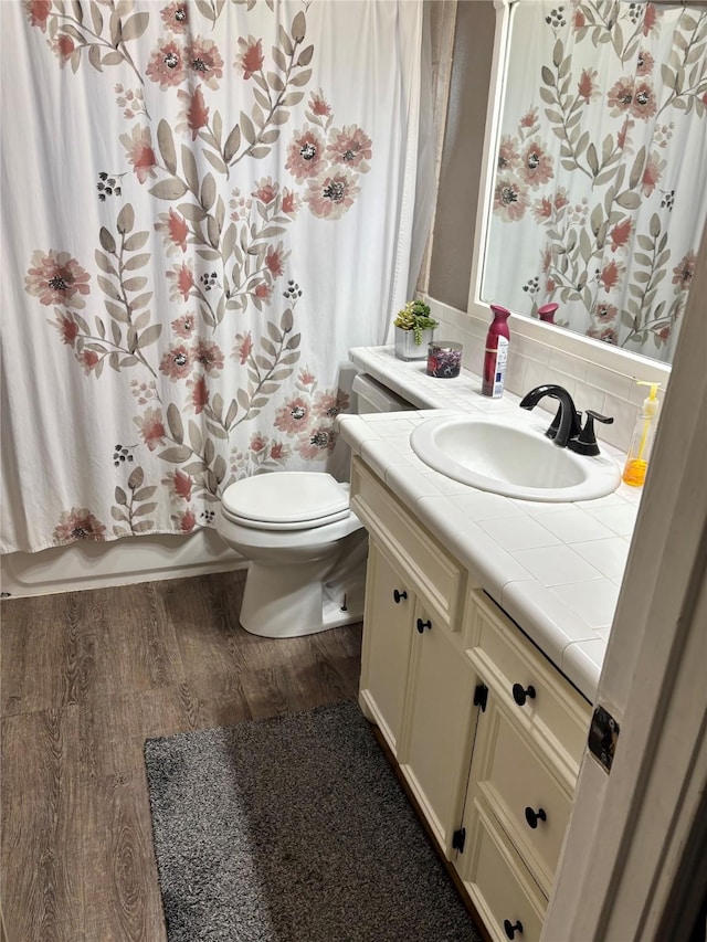 full bathroom with toilet, wood finished floors, vanity, decorative backsplash, and shower / bathtub combination with curtain