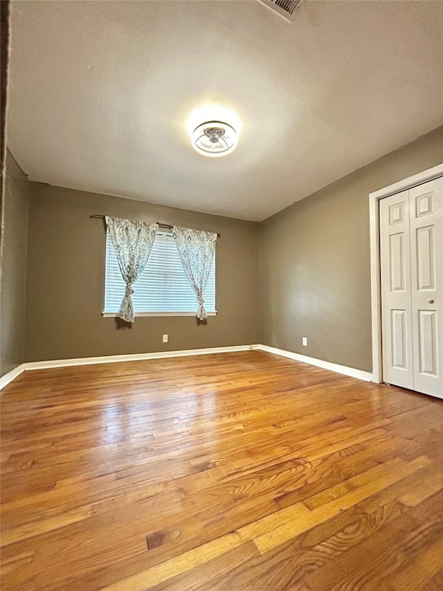 unfurnished bedroom featuring a closet, wood finished floors, and baseboards