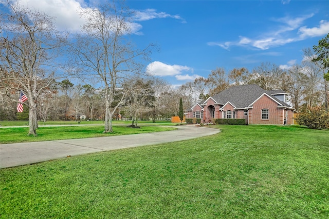 view of front of house featuring driveway, a front lawn, and brick siding