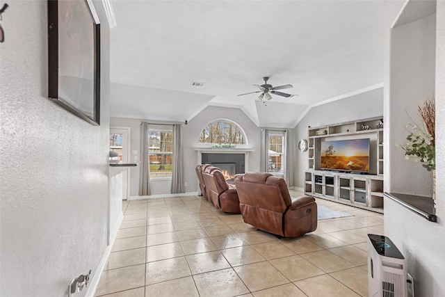 19475 Humaya, Porter, TX 77365 - living area featuring a ceiling fan, a lit fireplace, light tile patterned flooring, lofted ceiling, and crown molding