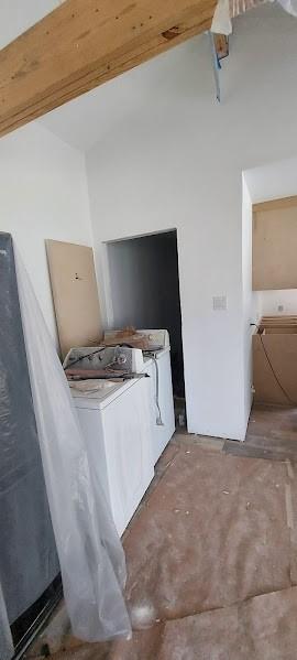 unfurnished bedroom featuring vaulted ceiling with beams and washing machine and dryer