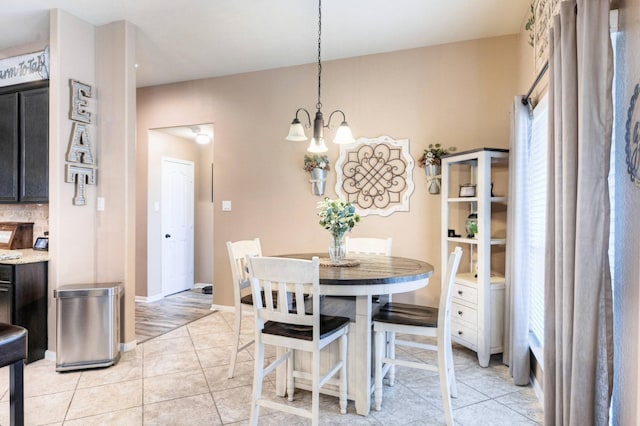 dining room featuring light tile patterned flooring, baseboards, and an inviting chandelier