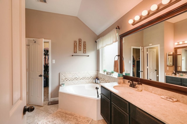 bathroom with vaulted ceiling, vanity, tile patterned floors, and a tub to relax in