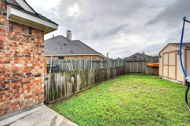 view of yard featuring a shed, a fenced backyard, and an outbuilding