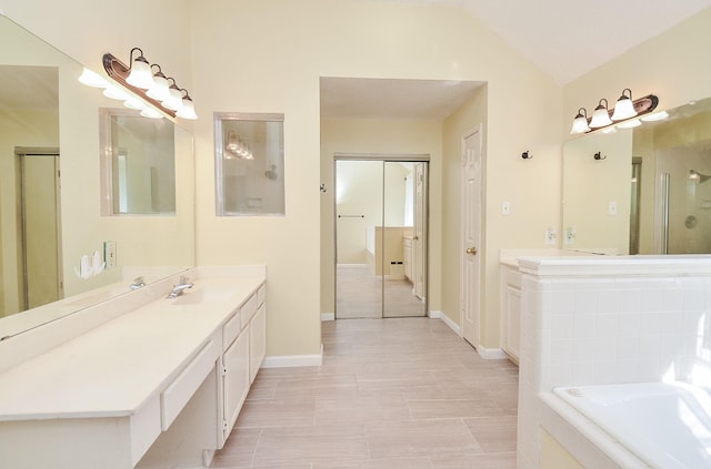 bathroom featuring tile patterned flooring, vanity, vaulted ceiling, and a relaxing tiled tub