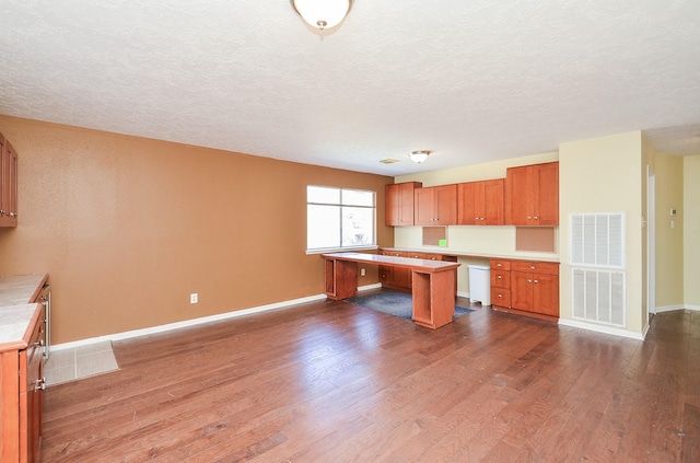 kitchen with built in desk, a kitchen breakfast bar, dark hardwood / wood-style floors, and a textured ceiling