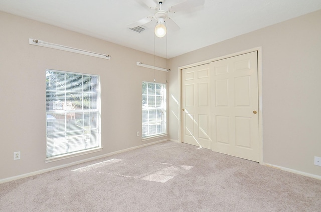 unfurnished bedroom featuring light carpet, a closet, and ceiling fan