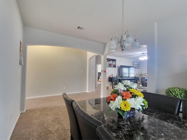 carpeted dining room with an inviting chandelier