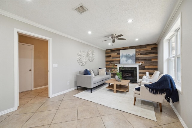 living room featuring wood walls, ornamental molding, light tile patterned floors, ceiling fan, and a textured ceiling