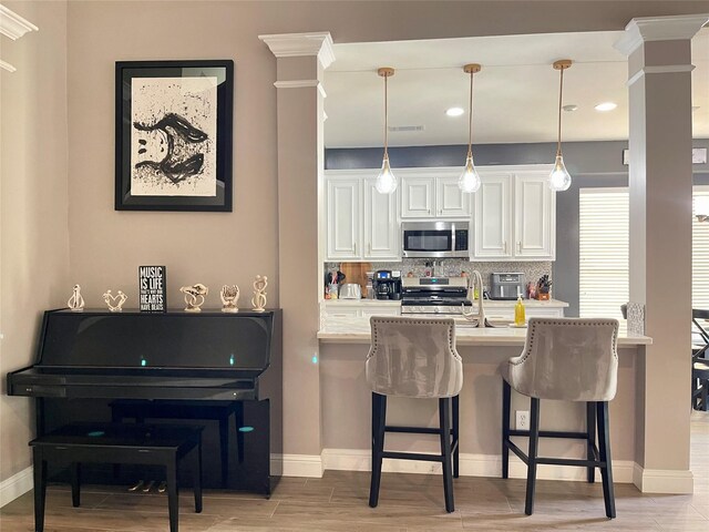 kitchen with white cabinetry, appliances with stainless steel finishes, a breakfast bar area, and backsplash