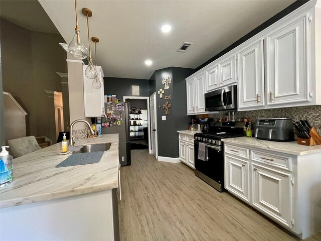 kitchen with white cabinetry, stainless steel appliances, light stone counters, and hanging light fixtures