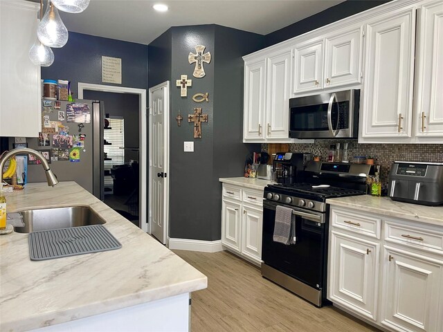 kitchen featuring white cabinetry, appliances with stainless steel finishes, sink, and light wood-type flooring