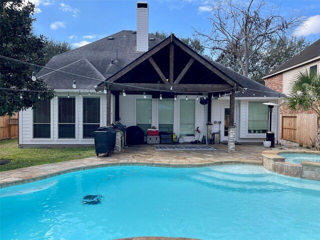 view of swimming pool with a grill, a patio area, and an in ground hot tub