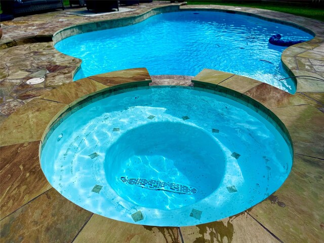 view of swimming pool with an in ground hot tub