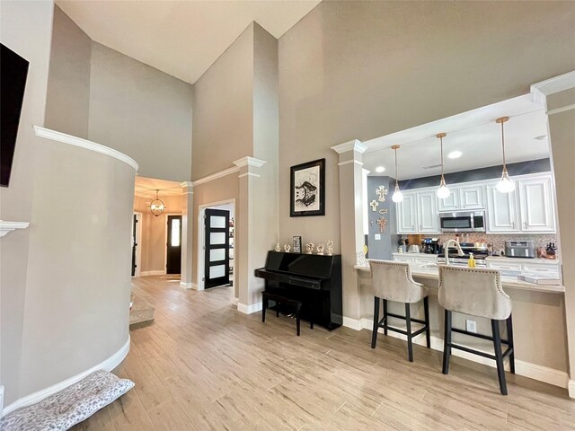 kitchen with white cabinets, a kitchen breakfast bar, kitchen peninsula, stainless steel appliances, and light wood-type flooring