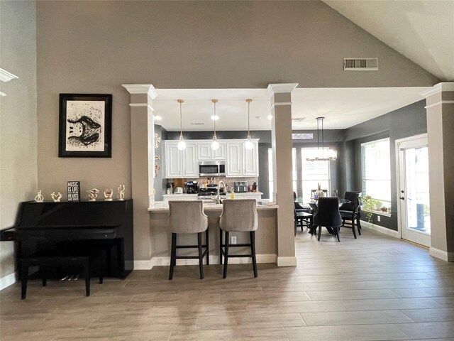 kitchen featuring a breakfast bar, appliances with stainless steel finishes, kitchen peninsula, pendant lighting, and white cabinets