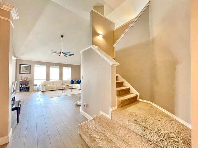 staircase with high vaulted ceiling, hardwood / wood-style floors, and ceiling fan