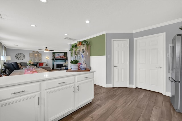 kitchen with stainless steel refrigerator, ceiling fan, dark hardwood / wood-style floors, ornamental molding, and white cabinets