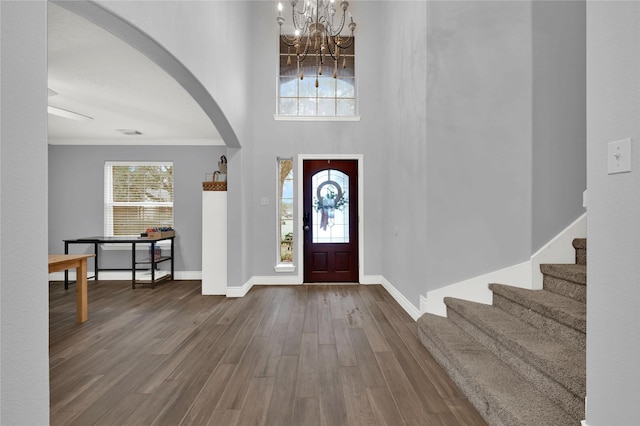 foyer with a high ceiling, ornamental molding, hardwood / wood-style floors, and an inviting chandelier