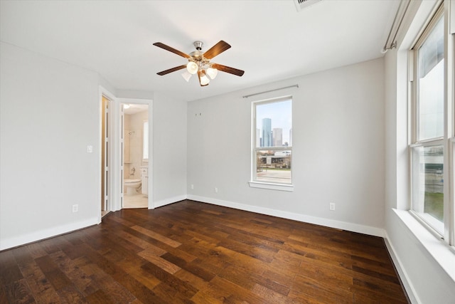 spare room featuring a wealth of natural light, dark hardwood / wood-style floors, and ceiling fan